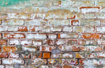 Old weathered brick wall. Peeling cracked paint on red brick	