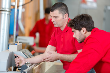 two workers operating on machine