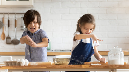 Little siblings preparing dough baking in kitchen together