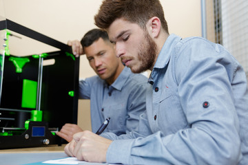 male worker making notes by 3d printer