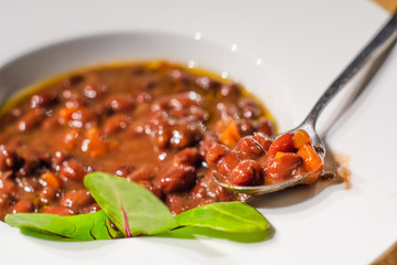 Frijoles rojos con un plato blanco y una cuchara al lado
