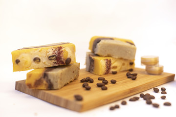 Natural cosmetic on the wooden board. The shadow of the fern. Coffee beans. Hand made soap and lip balm. White background
