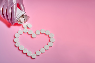 Doctor pours white pills from a bottle. Heart sign made from white pills on pink background, flat lay with space for text.