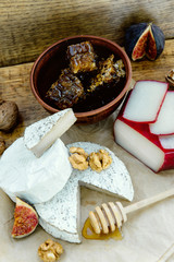 Rustic cheese platter with camembert, brie, gouda on wooden table,