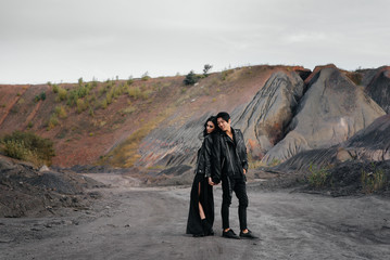 An Asian couple in love in black leather clothes walk in nature among the trees. Style, fashion, love