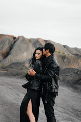 An Asian couple in love in black leather clothes walk in nature among the trees. Style, fashion, love