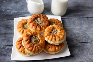 Fried belyashi on a plate and milk in a bottle. Patties with meat and onions.