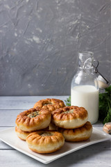 Fried belyashi on a plate and milk in a bottle. Patties with meat and onions.
