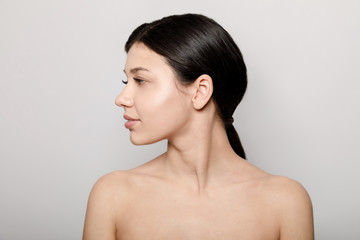 Side view portrait of brunette natural beauty with naked shoulders isolated light background