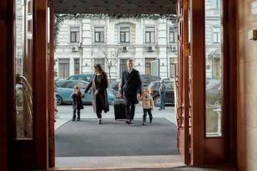 Arriving. Full-length shot of family of tourists, father, mother, daughter and son with a grey...