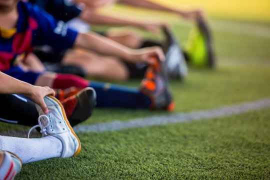 blurry image for sport background. Kid soccer players are stretching their hands to catch their feet. warming up the body and foot before the competition or practicing. - Powered by Adobe