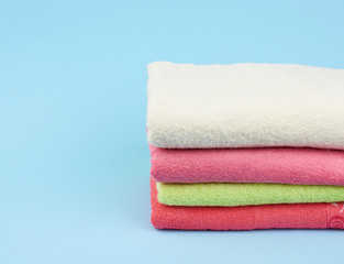 stack of colored cotton terry folded towels on a blue background