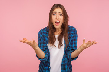 How could you? Portrait of indignant girl in checkered shirt raising hands asking what why, looking...