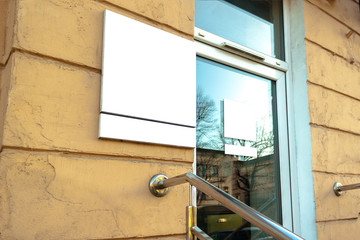 Mockup of the white blank square hanging logo sign in frame on the building wall or facade