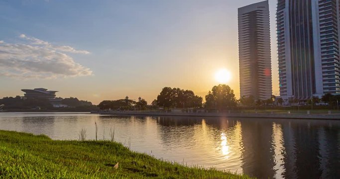 Sunset time lapse on the Putrajaya lake with four skyscraper behind the lake. The buildings reflecting in the lake. When it gets dark the lights come on and illuminating the scenery in awesome light. 