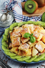 Austrian dessert Kaiserschmarrn served with sugar powder and kiwi fruit