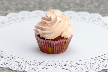 Cupcake with strawberry jam and whipped cream on a white napkin