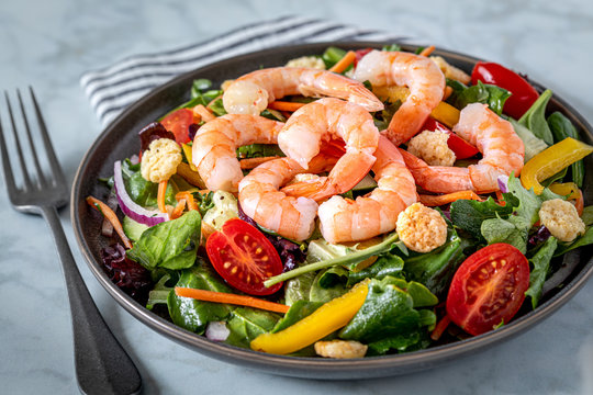Fresh shrimp and greens salad on light background