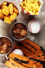 Chicken nuggets and french fries on the table with softdrink cola. Baseball party food with balls for the playoffs