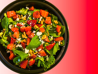 Mixed greens salad with strawberry and walnut isolated on Red FF3A00 gradient background.