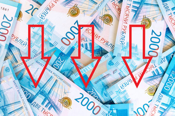 Background of paper russian money, banknotes of 2000 two thousands rubles with red down arrows as a...