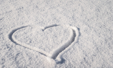 Fototapeta na wymiar Heart shape drawn on the white snow