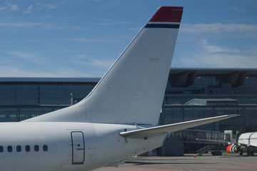 Fototapeta na wymiar Airplane tail on airport buildings background.