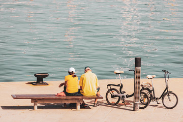 Older couple sitting in the harbor next to their bikes