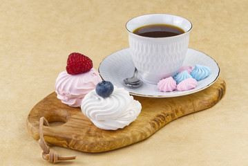 white coffee cup with a gold rim - coffee on an olive wood board. breakfast, coffee and bize cookies with raspberries and blueberries