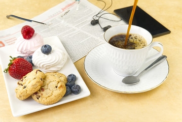 business breakfast, coffee and bize cookies with raspberries and blueberries. white coffee cup with a gold rim