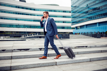 Handsome young businessman walking with suitcase
