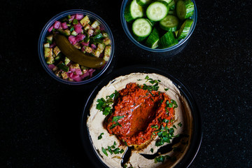 Muhammara hummus with salad and cucumber slices.
