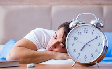 Man in bed frustrated suffering from insomnia with an alarm cloc