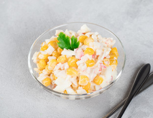 Salad of rice, corn, eggs and crab sticks in a bowl on a light background