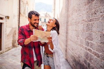 Sweet young couple using map in town