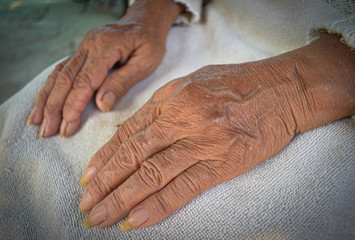Fototapeta premium Old woman with wrinkles with clearly visible wrinkles, putting her hands on the lap