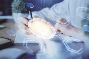 Cryptocurrency hologram, bitcoin, ico theme over hands taking notes background. Concept of blockchain. Multi exposure