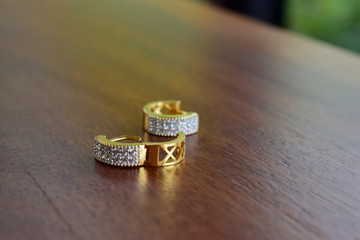 Gold earrings set with diamonds laid on the ground