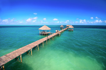 Palapas at the wooden peer on the tropical sea background, shallow focus
