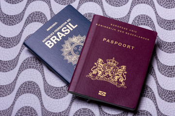 Brazilian and European - Dutch - passport on a wave pattern surface background. Concept double nationality with Copacabana print.