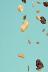 Falling pieces of seeds, nuts and raisins on a light background. Texture for design. Freezing in motion.