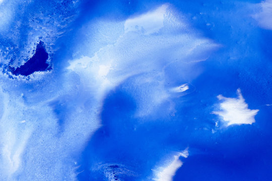 Classical blue and white watercolor paint in abstract spreading forms similar to satellite imagery with arctic snow hills and seas with glaciers melting in macro. Stains of paint in macro for design.