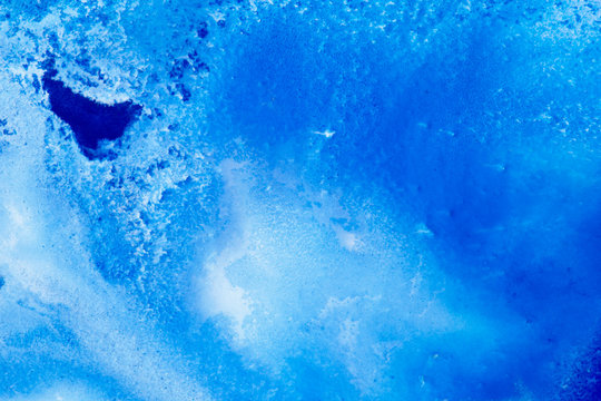 Classical blue and white watercolor paint in abstract spreading forms similar to satellite imagery with arctic snow hills and seas with glaciers melting in macro. Stains of paint in macro for design.