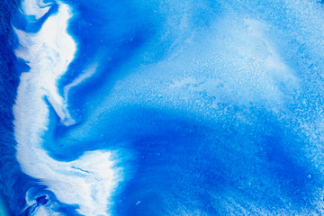 Classic blue and white watercolor paint in abstract flowing shapes for design in close-up. Background texture of unusual stains of blurry blue thick paint with sprinkles for text and lettering.