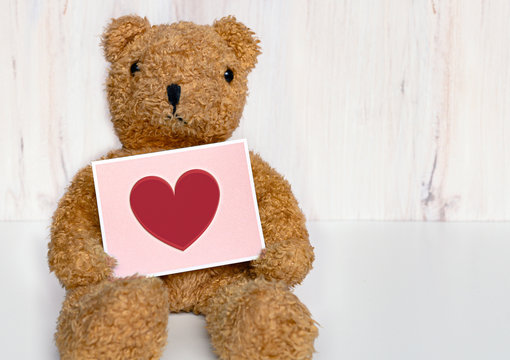 Teddy bear holding card with a heart on it, for get well, I love you, happy mother's day message