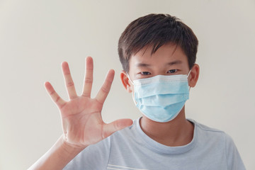 Asian preteen boy wearing medical face mask and making stop sign, coronavirus, covid-19  virus pandemic, pm 2.5 air pollution,  stop Asian hate concept