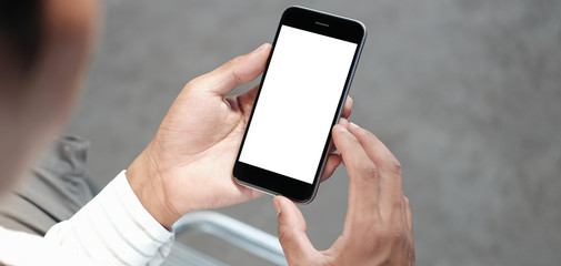 Cropped shot view of man hands holding smart phone with blank copy space screen for your text message or information content, female reading text message on cell telephone during in urban setting. 