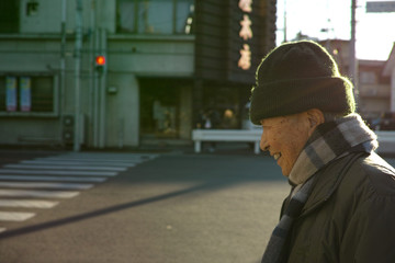 An old Asian man walking down the road in Winter