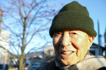 An old Asian man wearing a wooly hat in the Winter