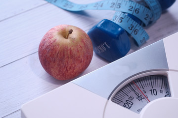 Close up of apple, dumbbell and weight machine on table 